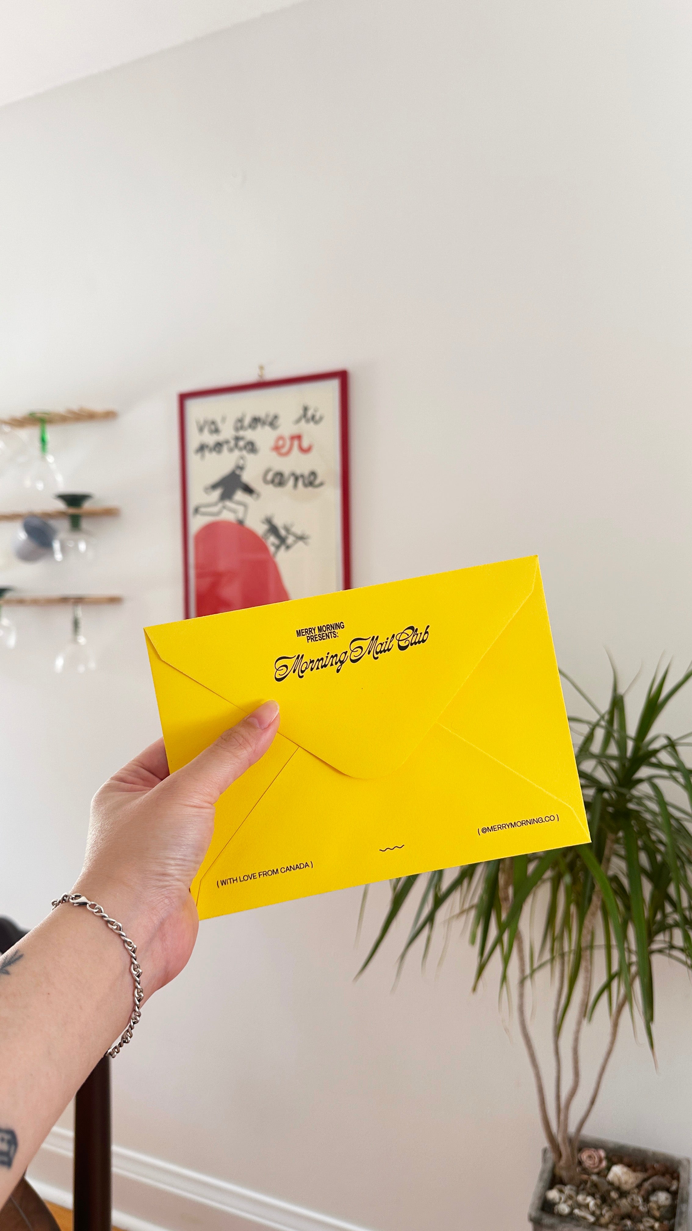 Hand holding a yellow envelope with text against a neutral background