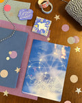 Notebooks, a mug, and decorative items on a wooden surface with confetti.